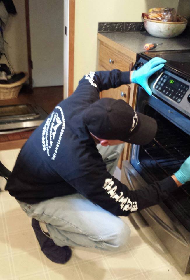 The owner of Advanced Appliance Solutions repairing an oven